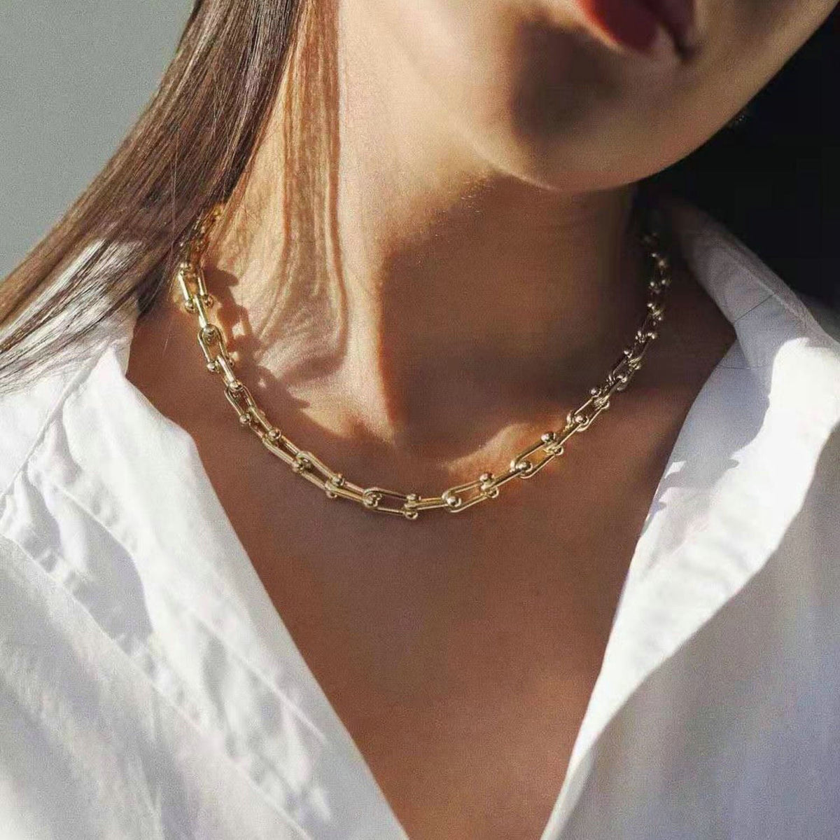 Woman in a white shirt wearing the Cascade chunky gold link chain necklace at the base of the neck