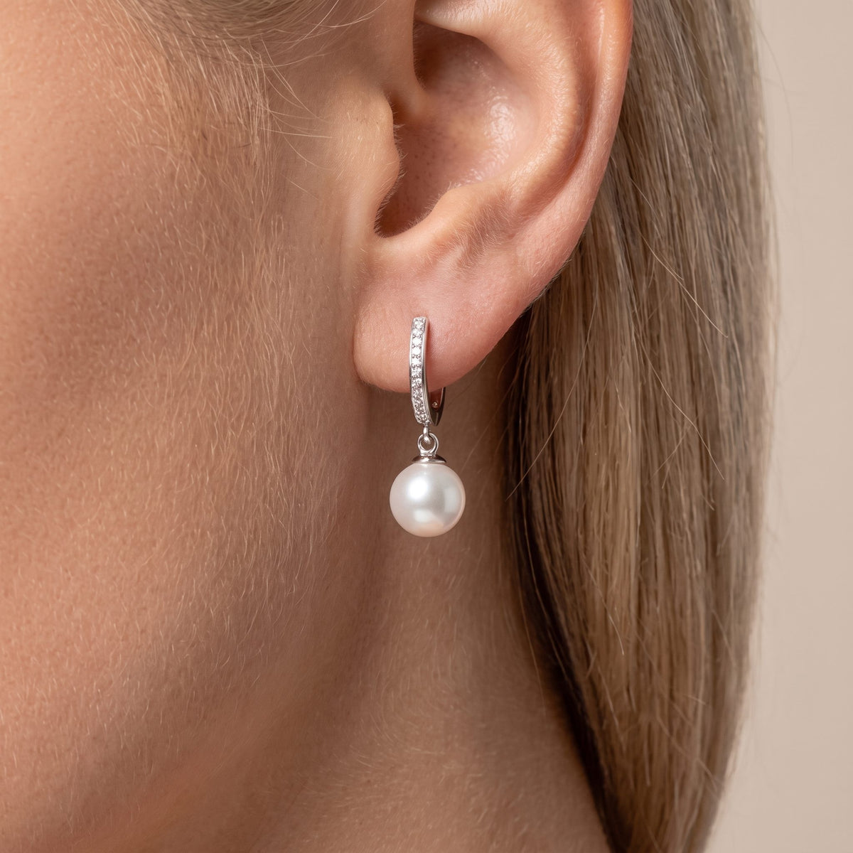 Woman wearing the Anaïs pavé pearl earring in silver, a round pearl below a crystal huggie