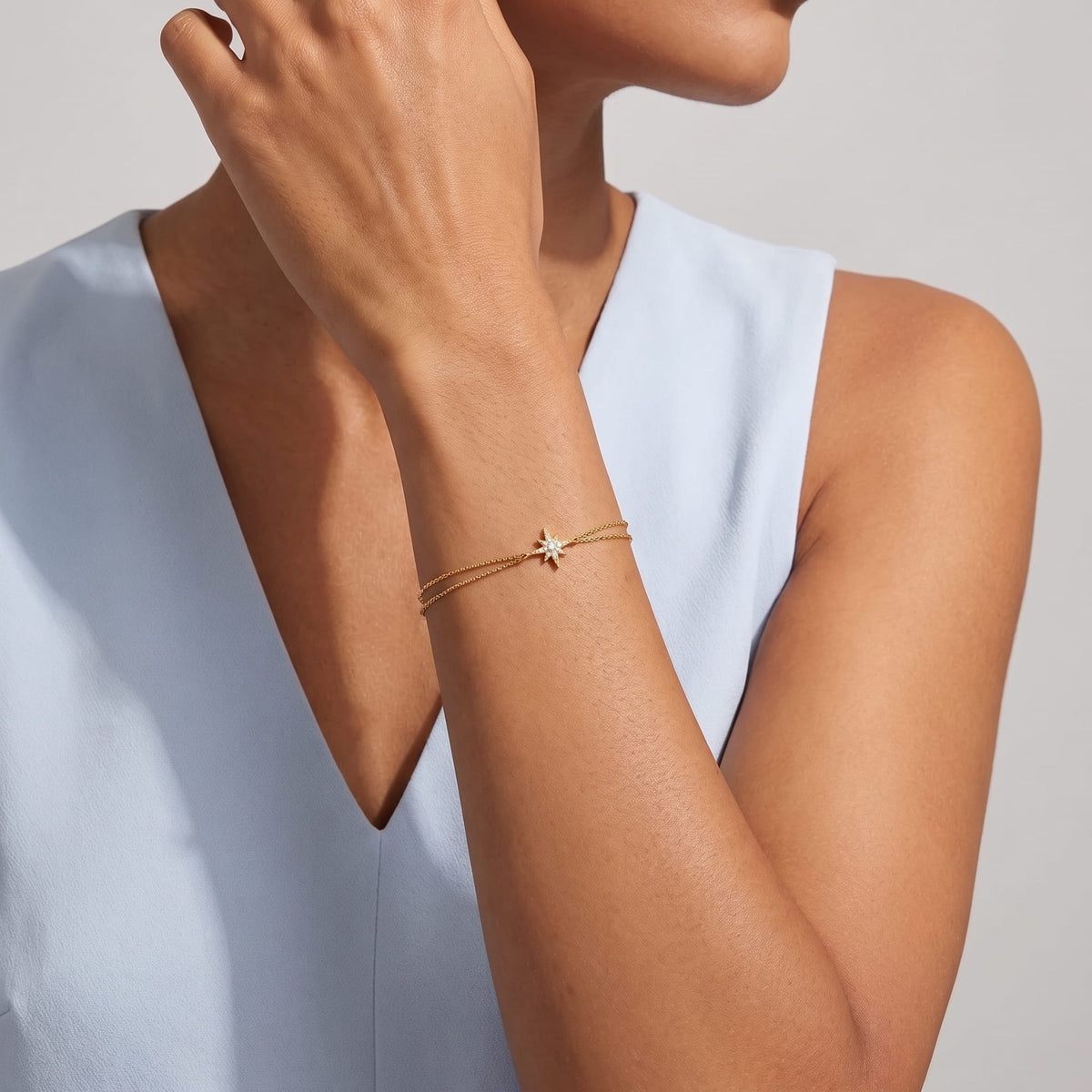 Woman wearing the Astrid north star gold bracelet on the wrist paired with a light blue top