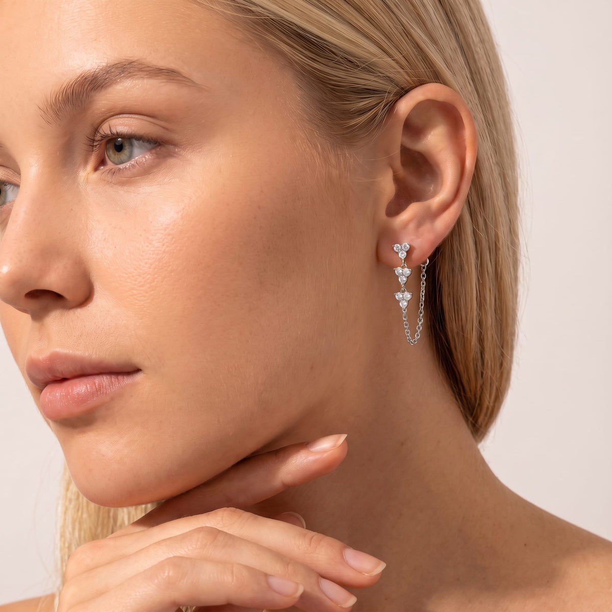Woman wearing the Bettina crystal cascade silver earrings on her ear with her hand on chin
