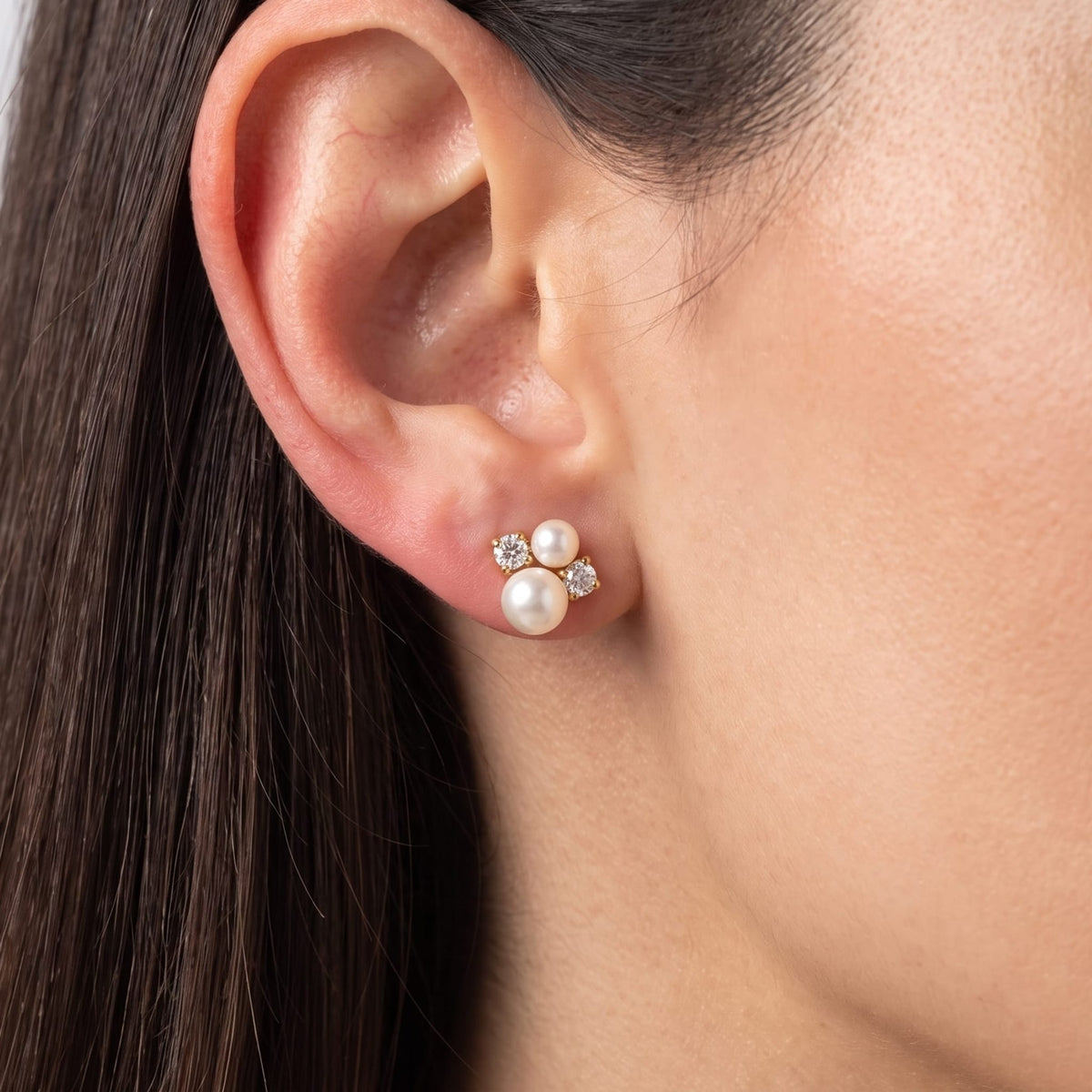 Woman wearing the Blanche pearl cluster gold earrings on her earlobe in a close-up profile view