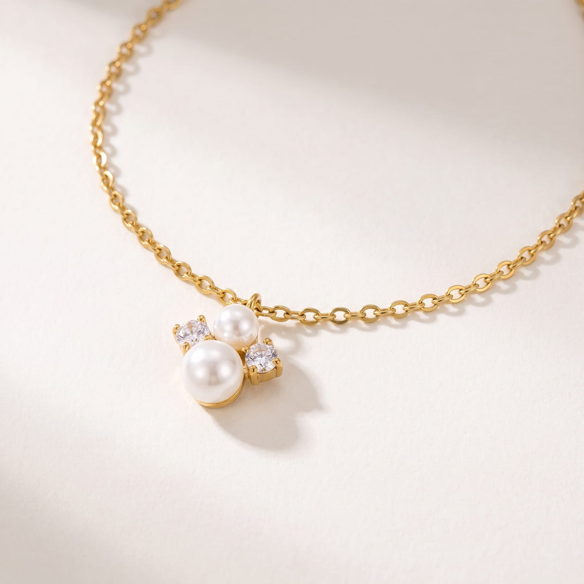 Blanche pearl cluster gold necklace on a off-white surface showing close-up details of the pendant cluster