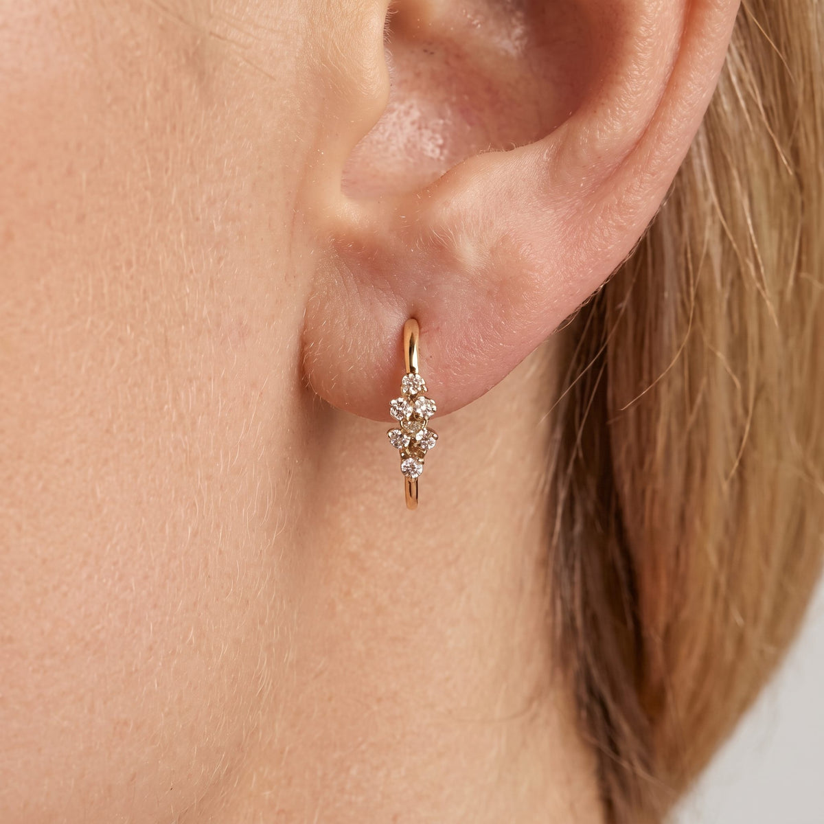 Woman wearing a slim Camille gold hoop with a small crystal cluster at the front, close to the lobe