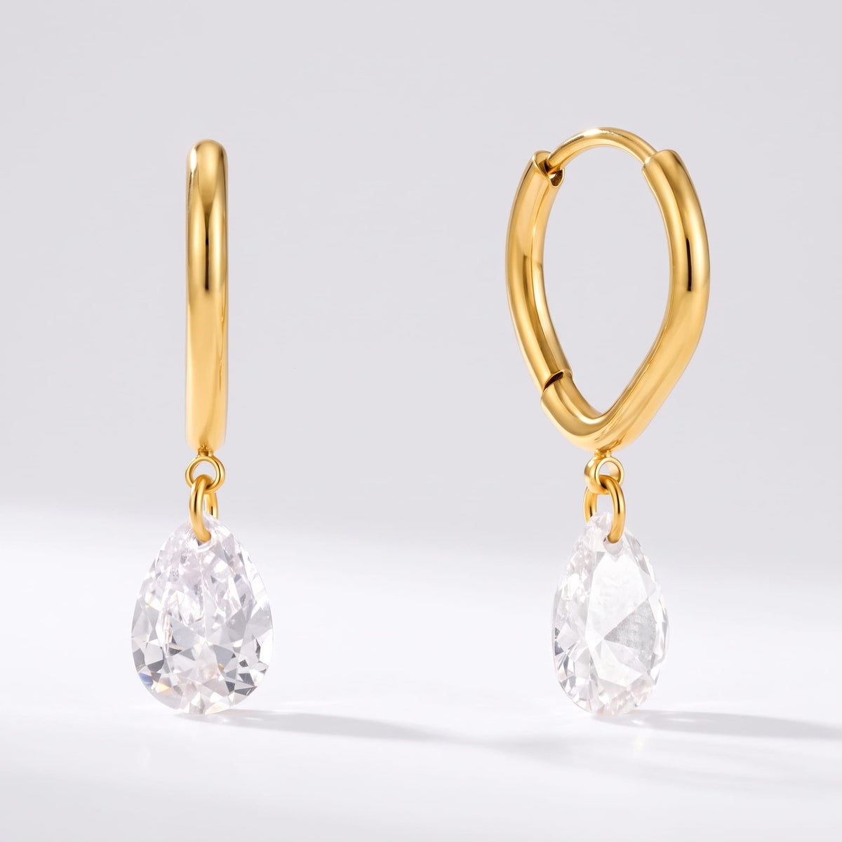 Carla teardrop huggie gold earrings on a white surface showing two different angles