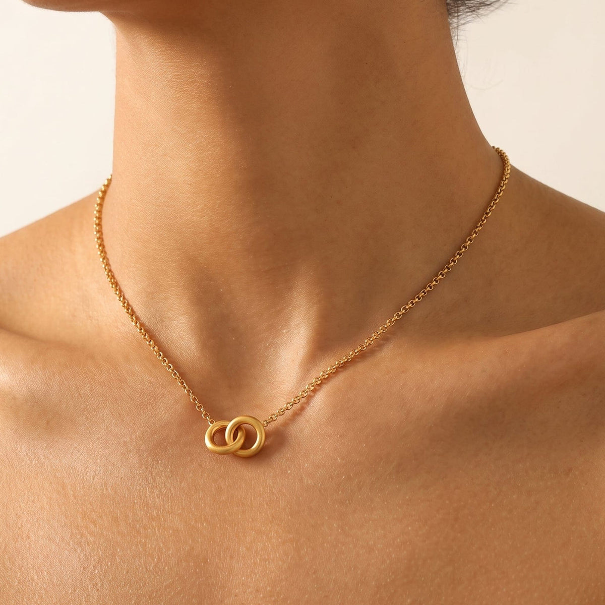 Woman wearing the Colette interlocking rings gold necklace at the collarbone