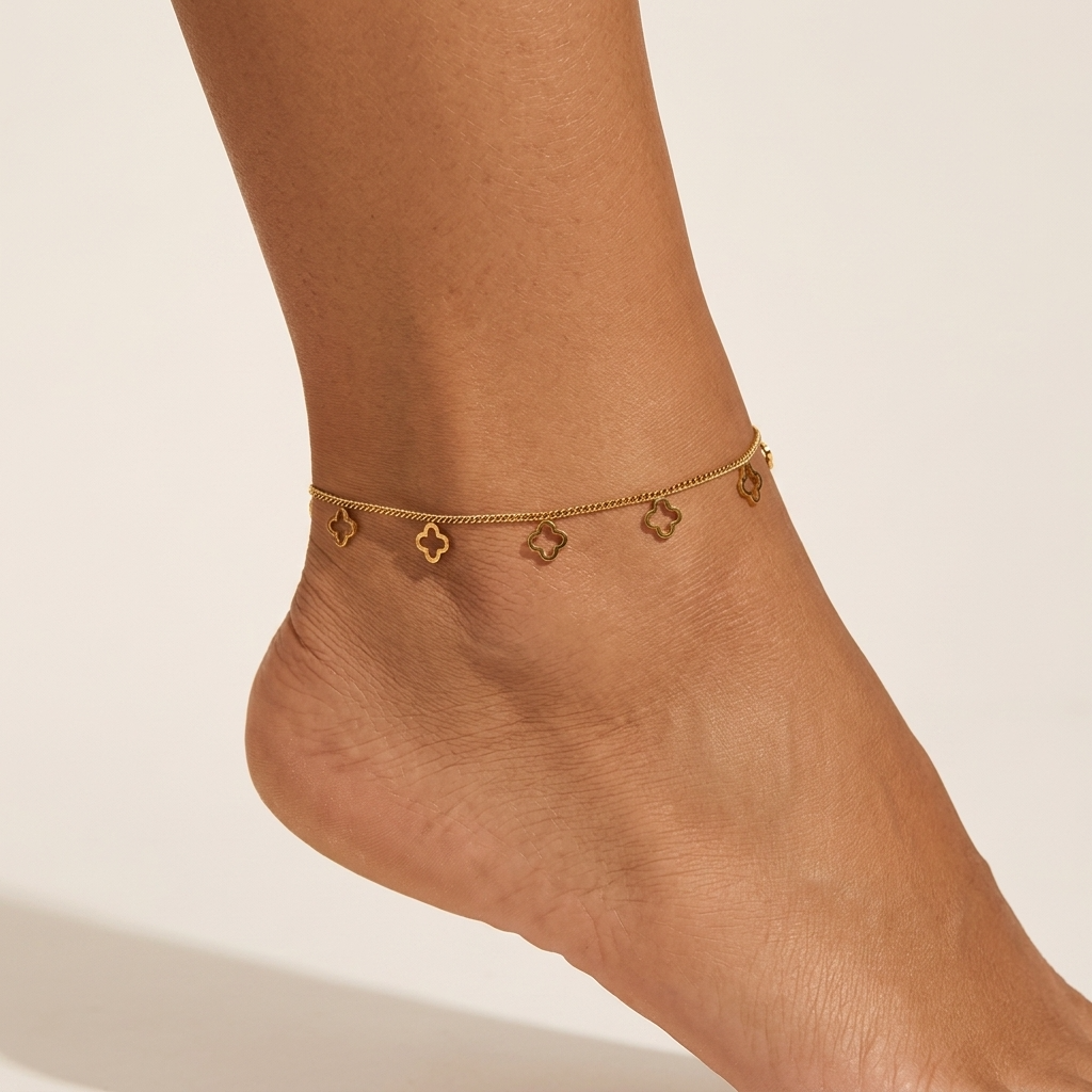 Camille clovers anklet on the ankle, slim gold curb chain with open cut-out clover charms