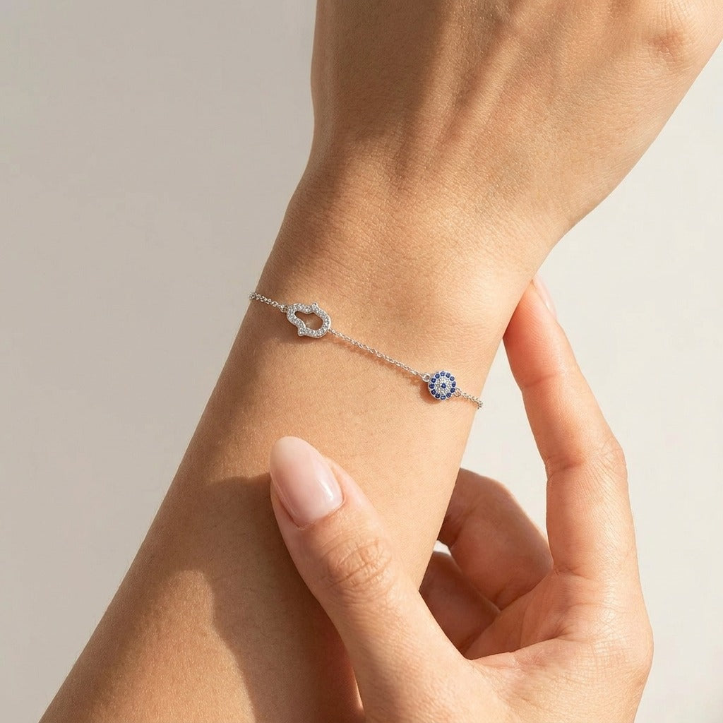 Woman wearing the Chloé silver bracelet with a crystal hamsa hand and a blue evil eye charm