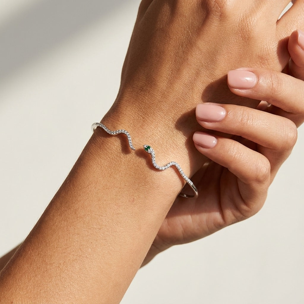 Woman wearing the Liana silver snake cuff with a crystal-lined body and a green eye stone