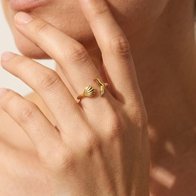 Woman wearing the Ocean gold ring with a seashell and whale tail at its open ends