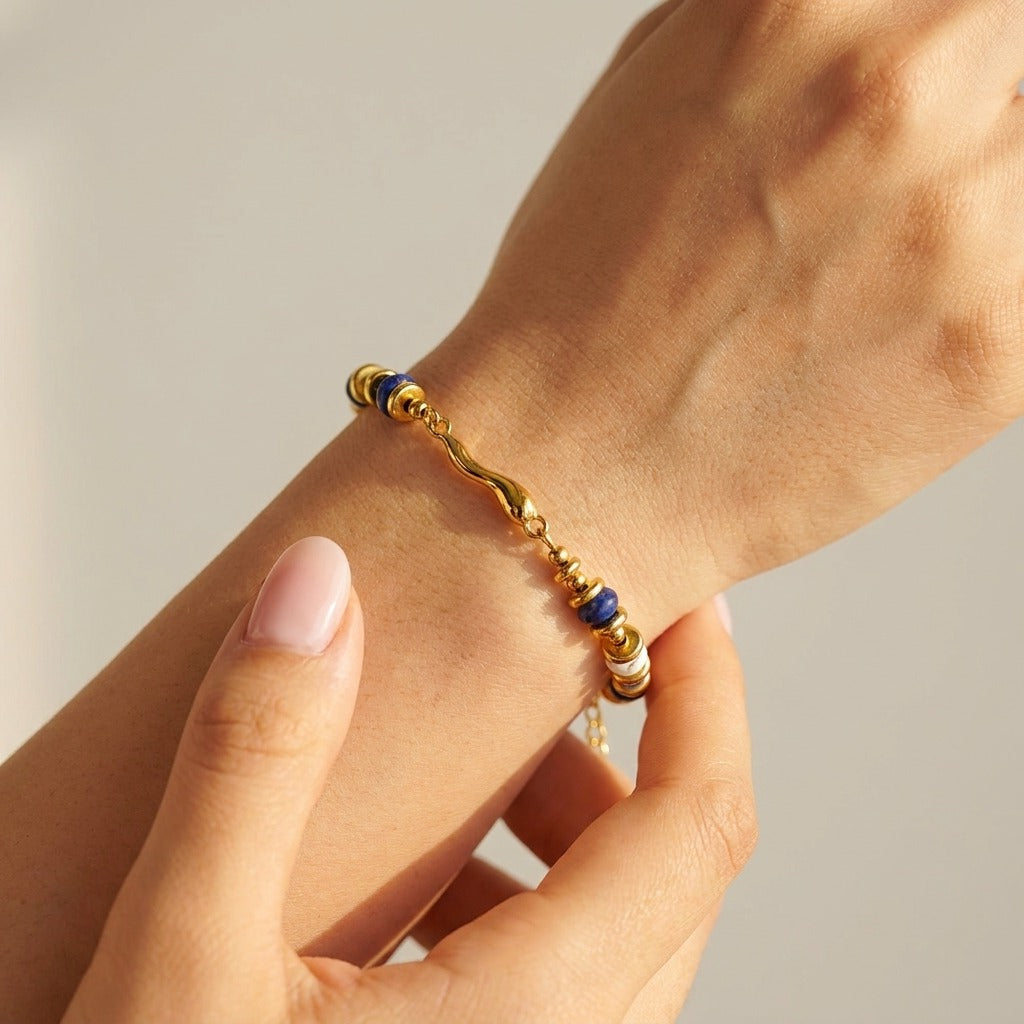 Woman wearing the Quintessa bracelet, navy beads and a wavy gold bar on a single strand, on the wrist