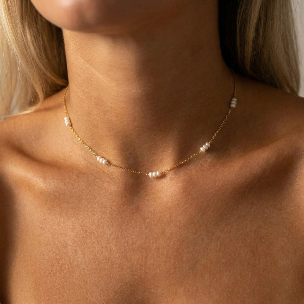 Woman wearing the Valentina tiny pearls necklace in gold, seed pearl clusters at the collarbone