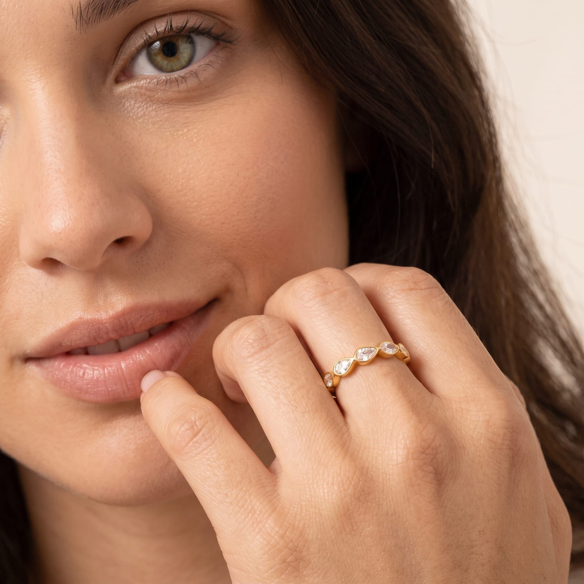 Woman wearing the Élodie pear eternity gold ring on the hand touching her lip