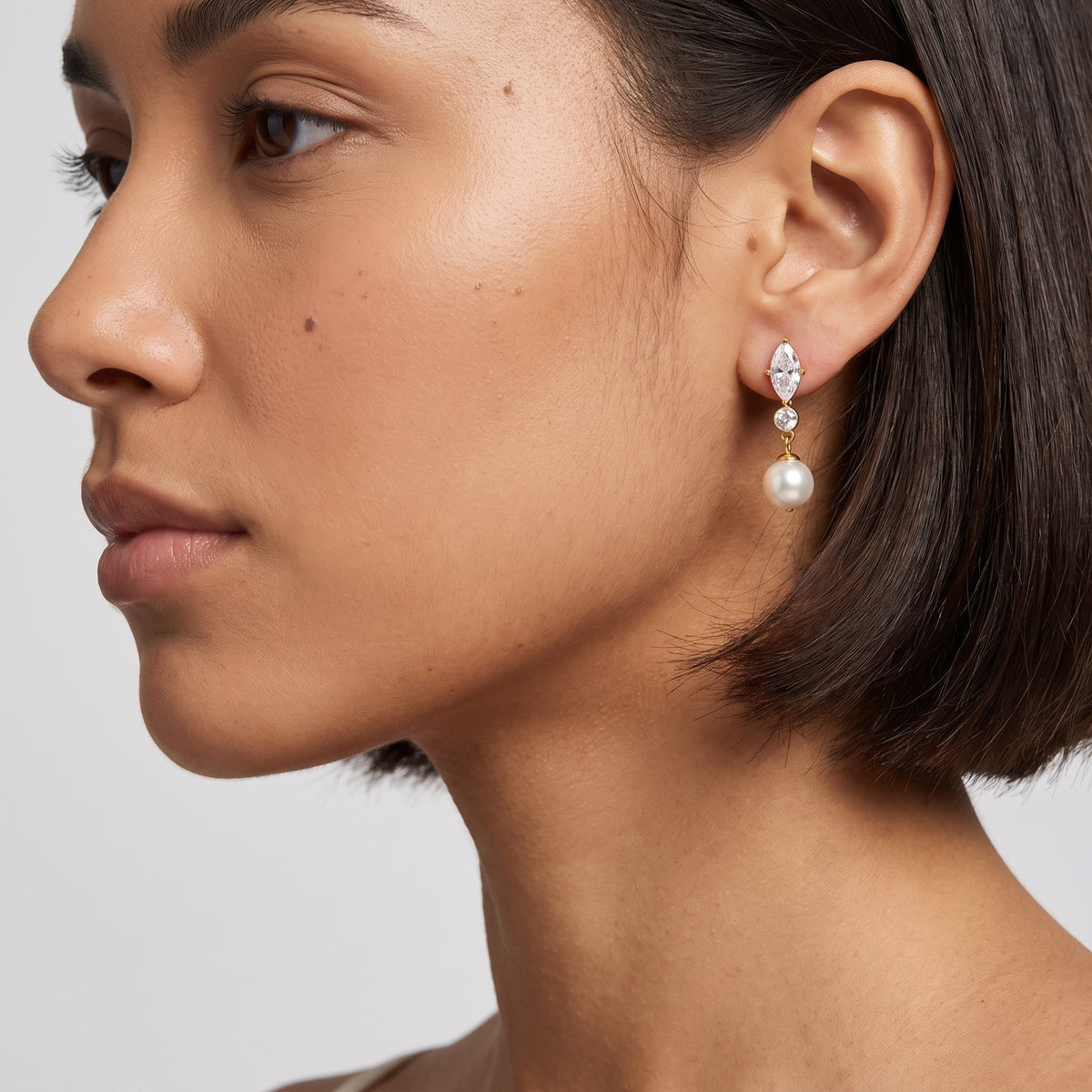 Woman wearing the Emilia marquise pearl gold earrings on her ear turned in profile view