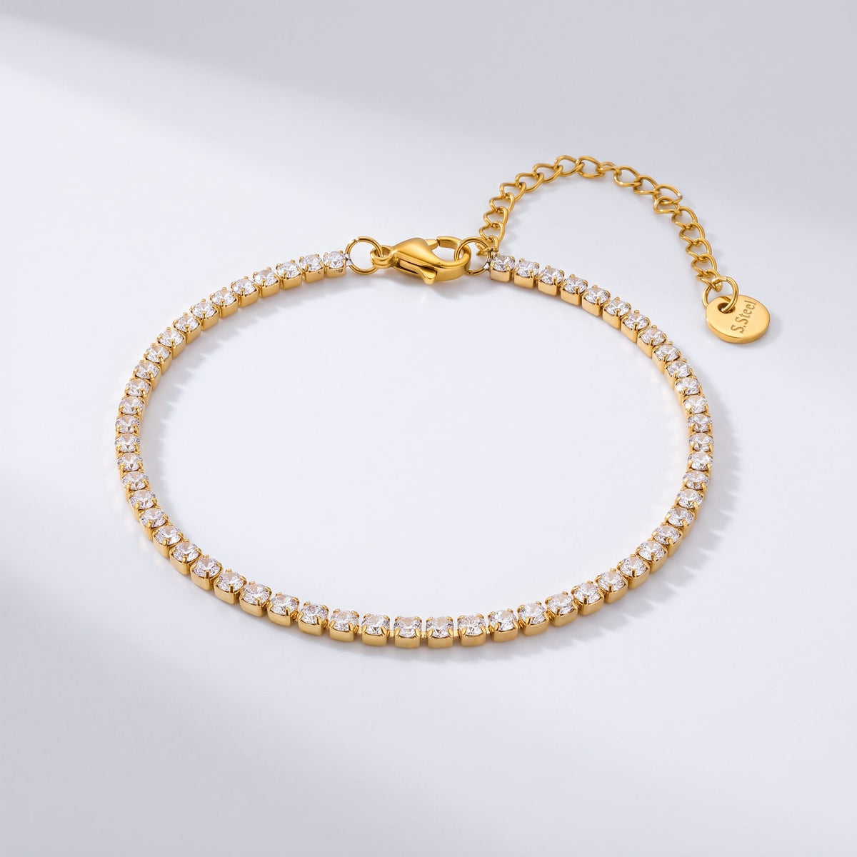 The Emma tennis chain gold bracelet on a light gray background