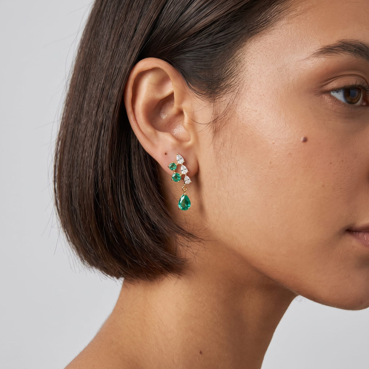 Woman wearing the Florentine green cascade gold earrings on her ear with short dark hair