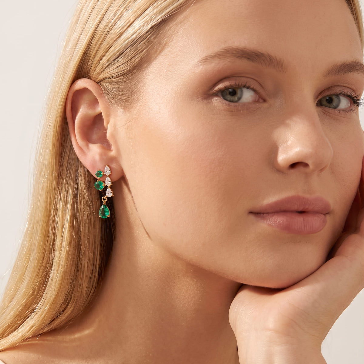 Woman wearing the Florentine green cascade gold earrings on her ear resting her chin on hand