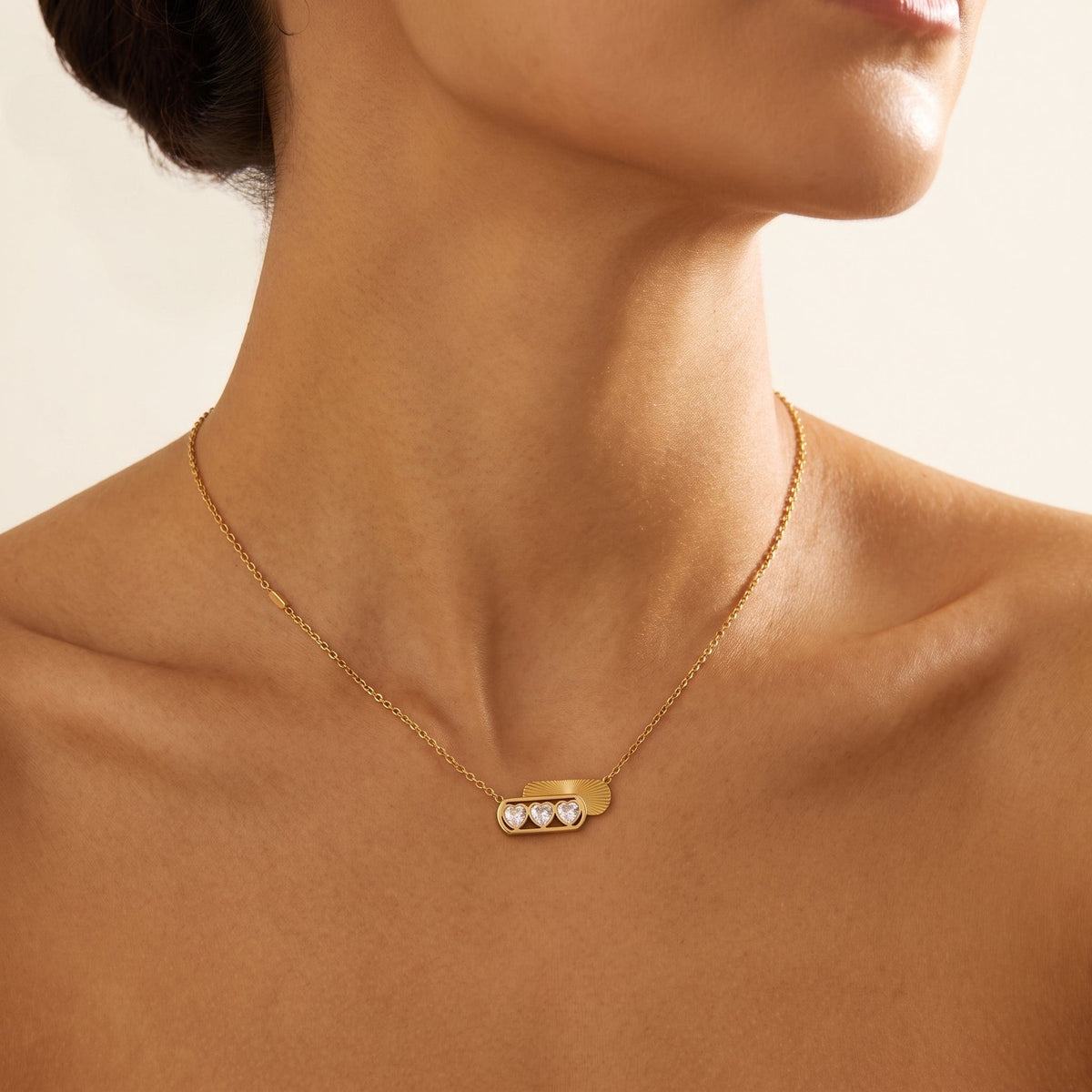 Wider view of a woman wearing the Ginevra triple heart gold necklace at the collarbone