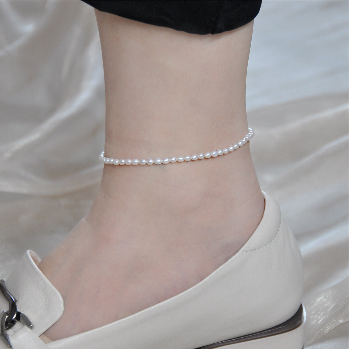 Olivia petite pearl anklet on the ankle, a strand of tiny white pearls worn with a cream loafer
