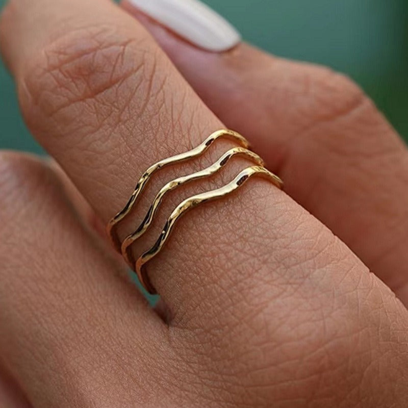 Woman wearing the Sea Wave gold ring, three hammered wavy bands stacked on one finger