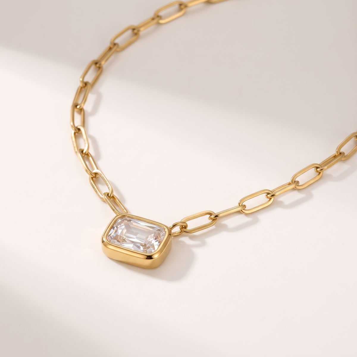 Isabelle emerald cut gold necklace on a white surface with soft shadows