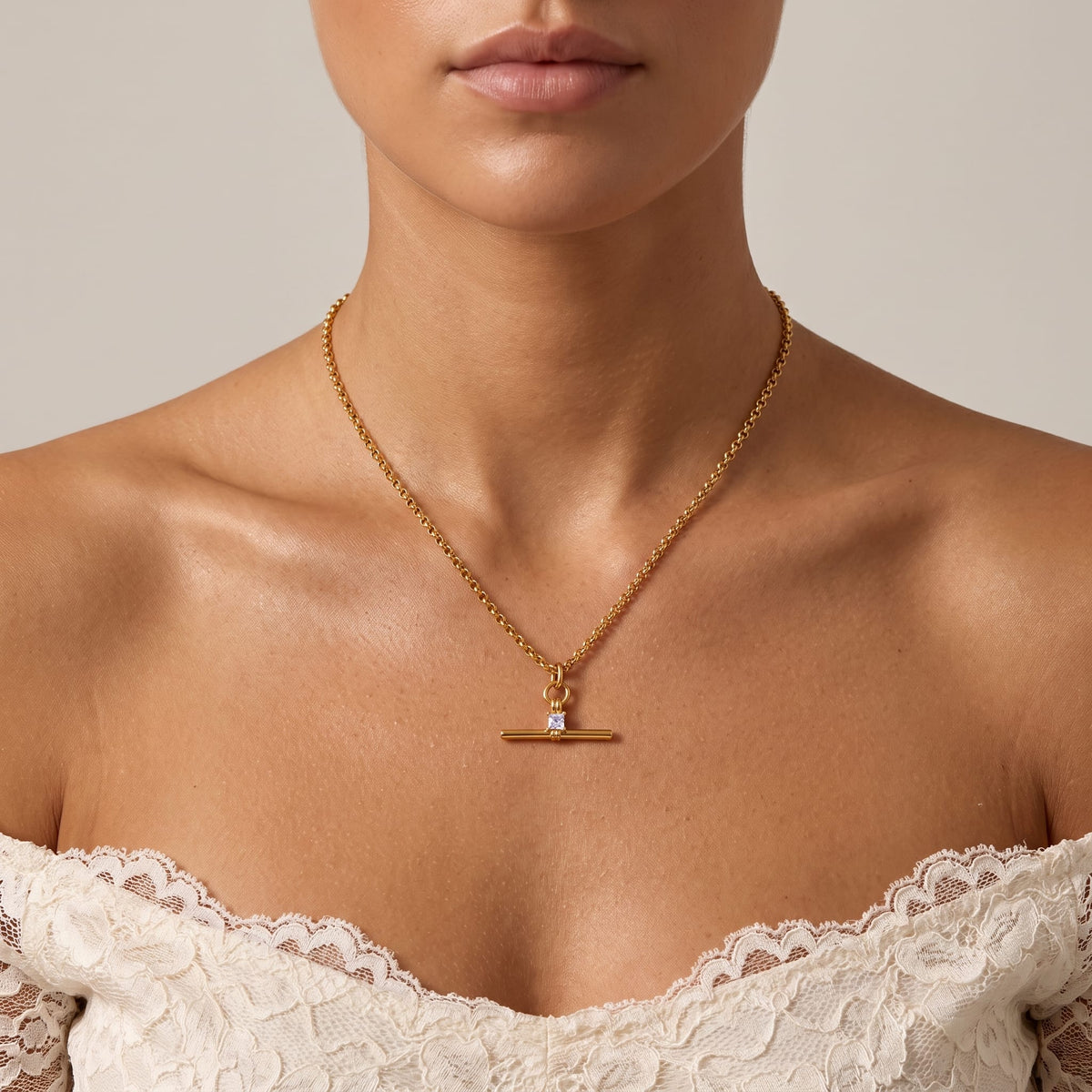 Woman wearing the Joséphine t-bar crystal gold necklace at the collarbone in a lace off-shoulder top