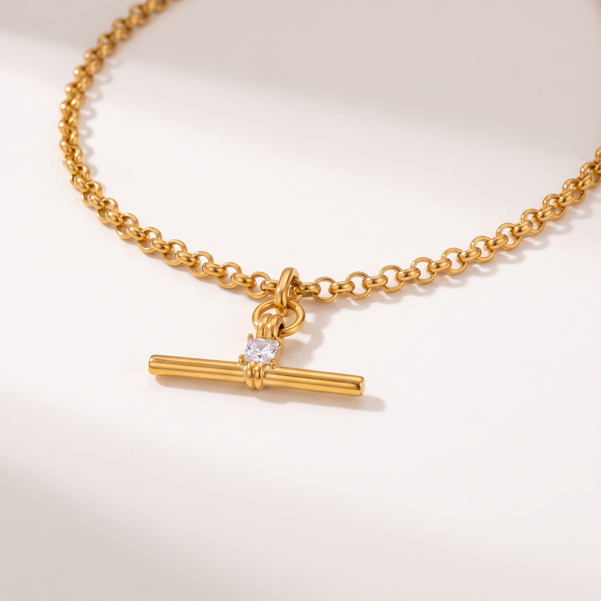 Joséphine t-bar crystal gold necklace on a neutral surface showing the t-bar pendant and rolo chain close up