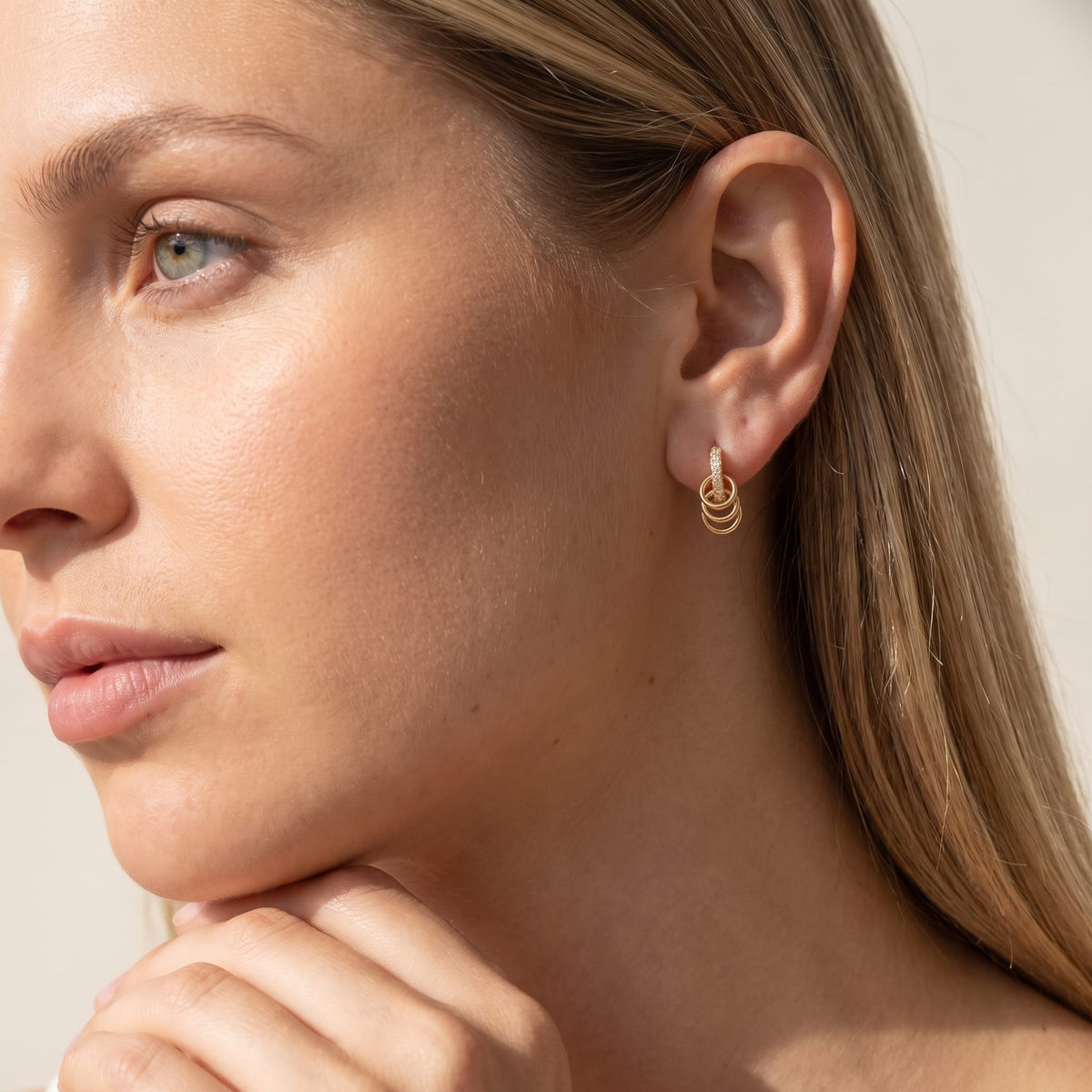 Woman wearing the Joséphine triple loop gold earrings on the ear with hand resting on chin