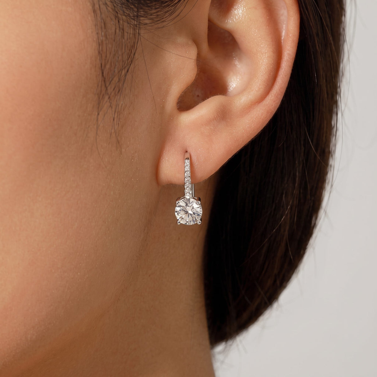 Woman wearing the Luna silver earring, a round solitaire crystal below a short pavé bar