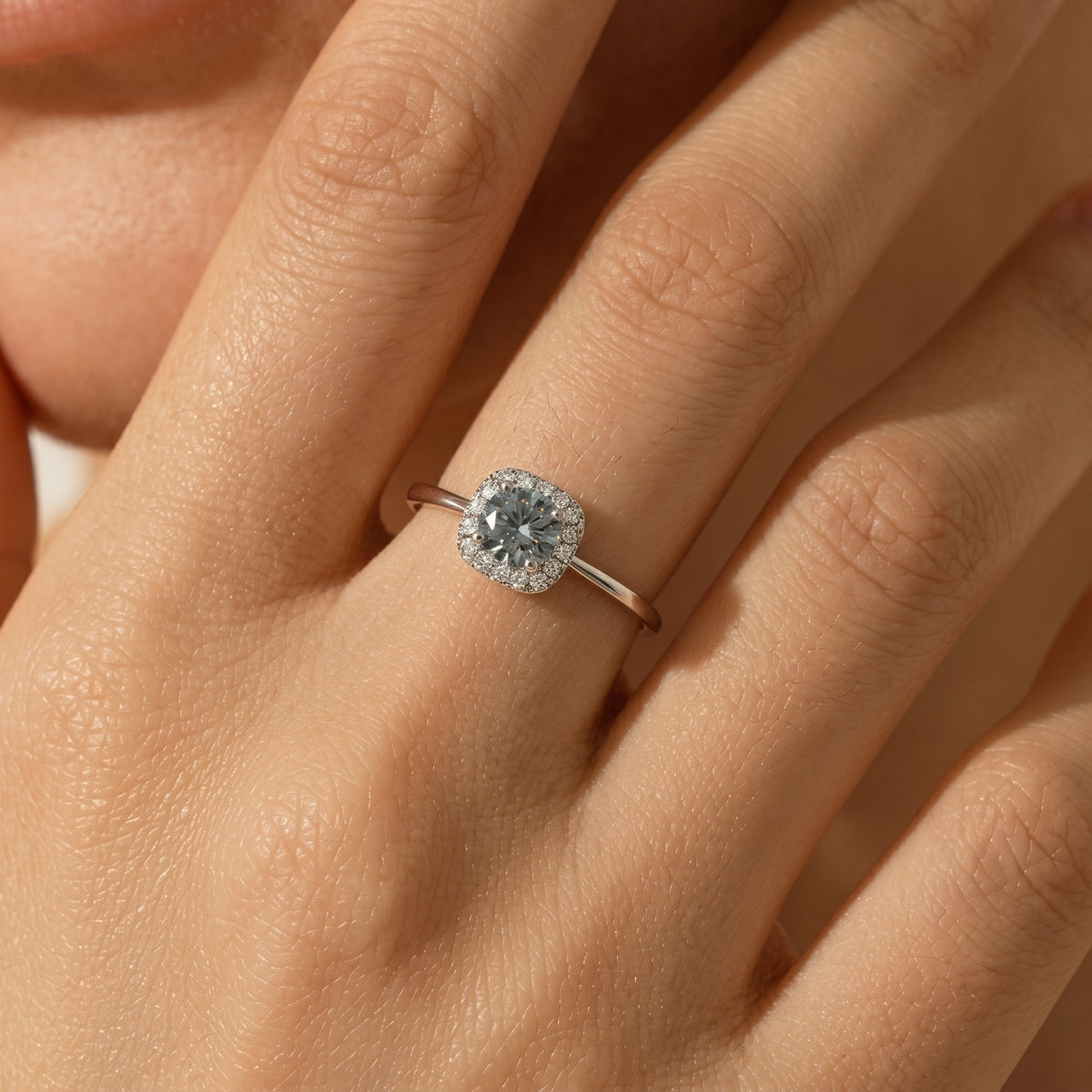 Woman wearing the Isabelle halo silver ring, a round center stone framed by a cushion-shaped crystal halo
