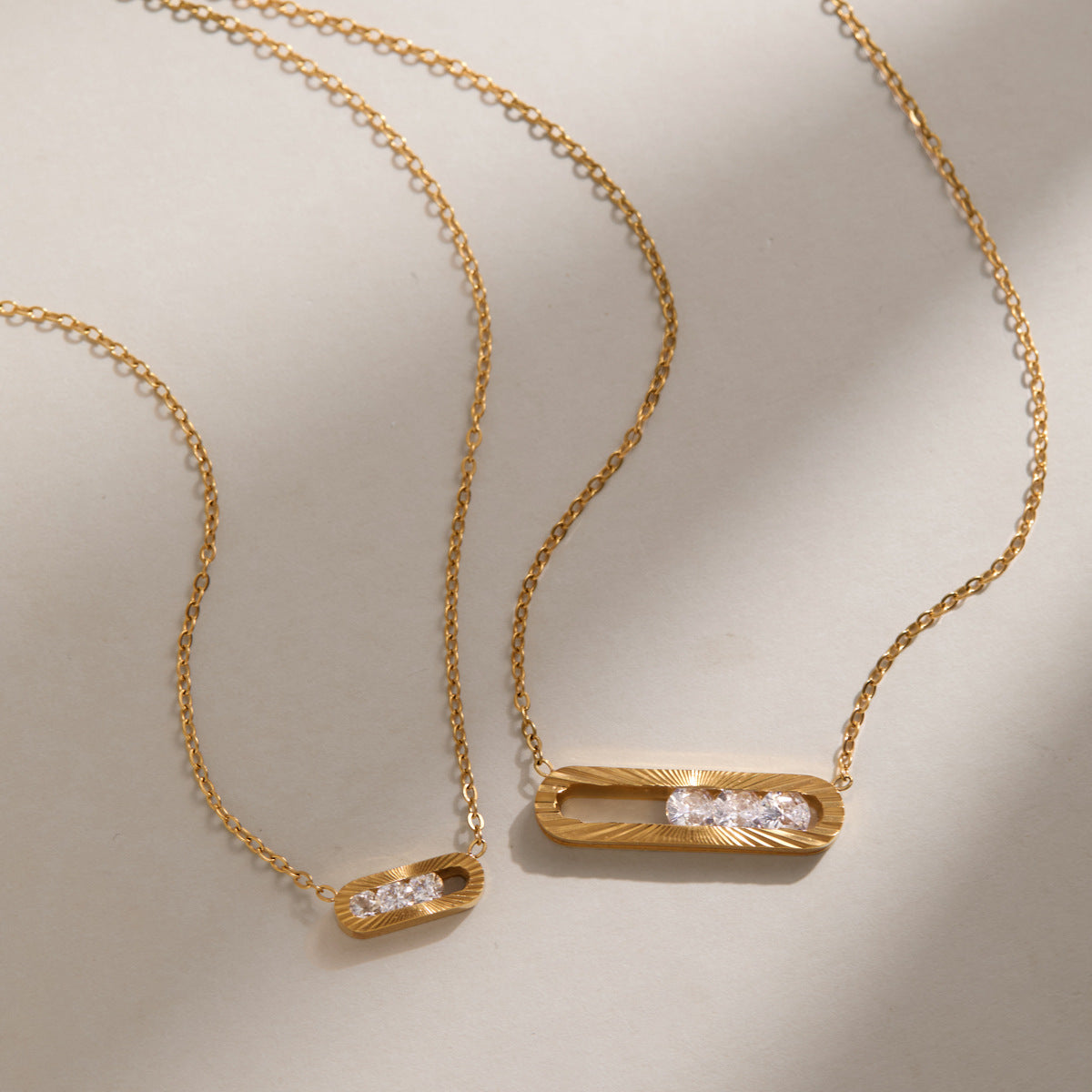 Small and large Margaux sliding crystal necklaces side by side on a cream surface