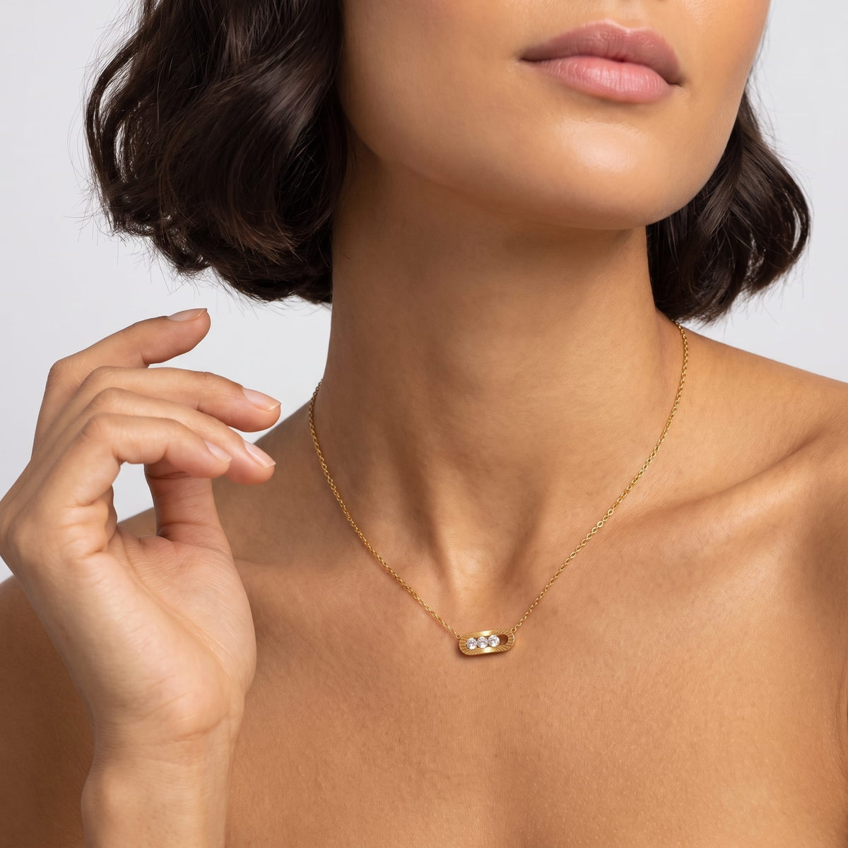 Woman wearing the Margaux sliding crystal gold necklace at the throat with hand near jawline