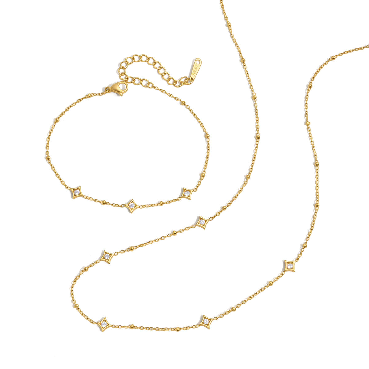 Océane star station gold necklace curving beside the matching bracelet on a white background