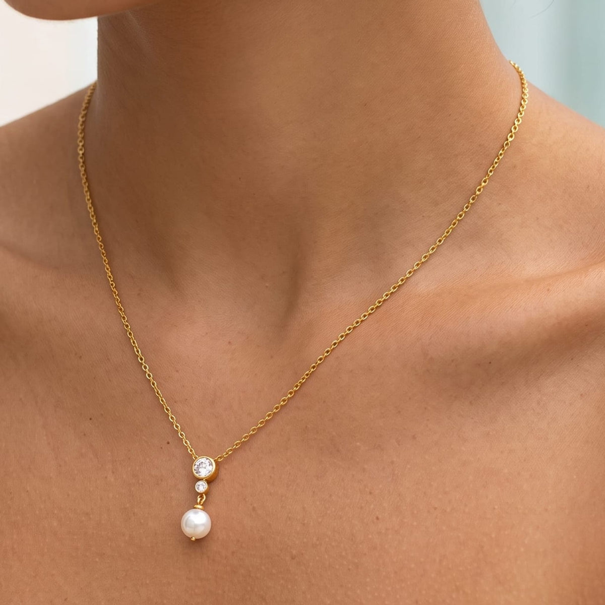 Woman wearing the Odette crystal pearl gold necklace at the collarbone in a white lace top