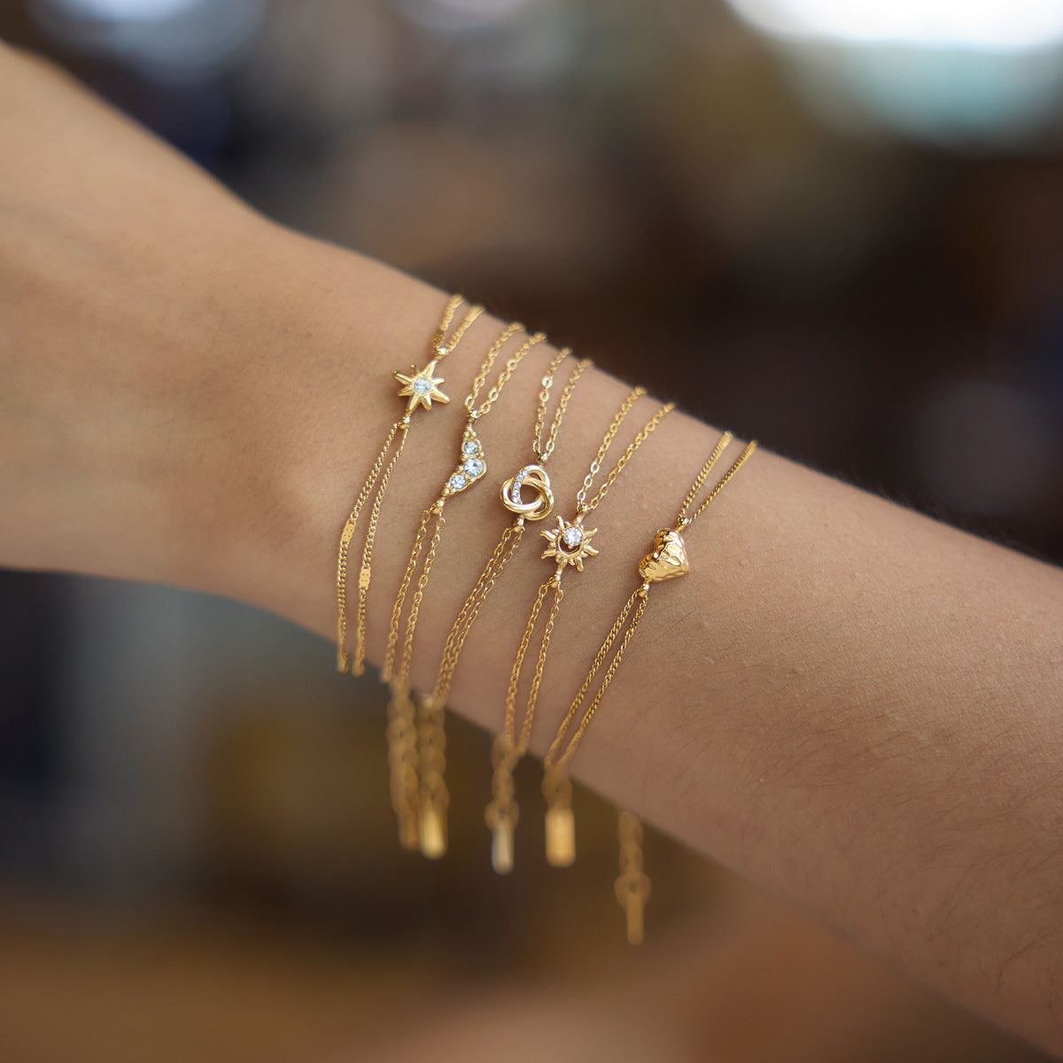 Olivia sun charm bracelet stacked on the wrist with other fine gold charm bracelets