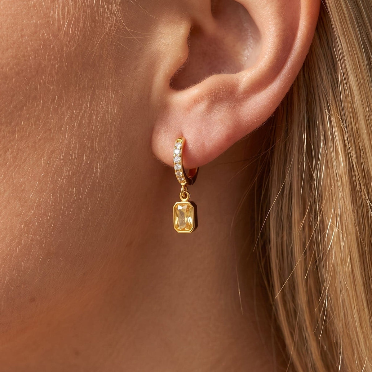 Woman wearing the Paola yellow octagon gold earrings on the ear
