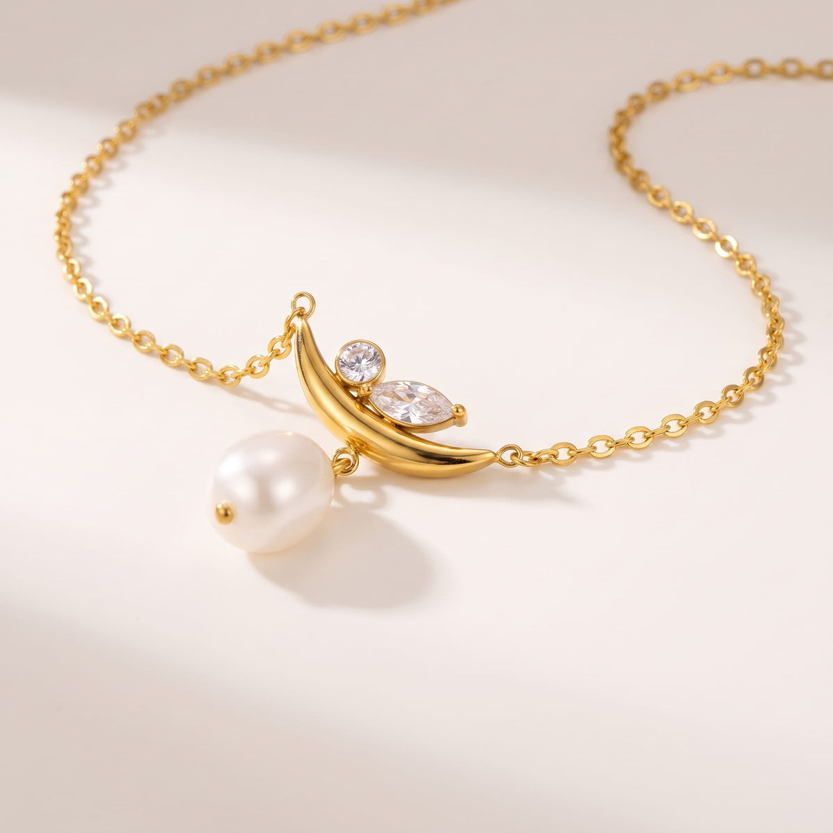 Pauline moon pearl gold necklace on a white surface with soft light and shadows
