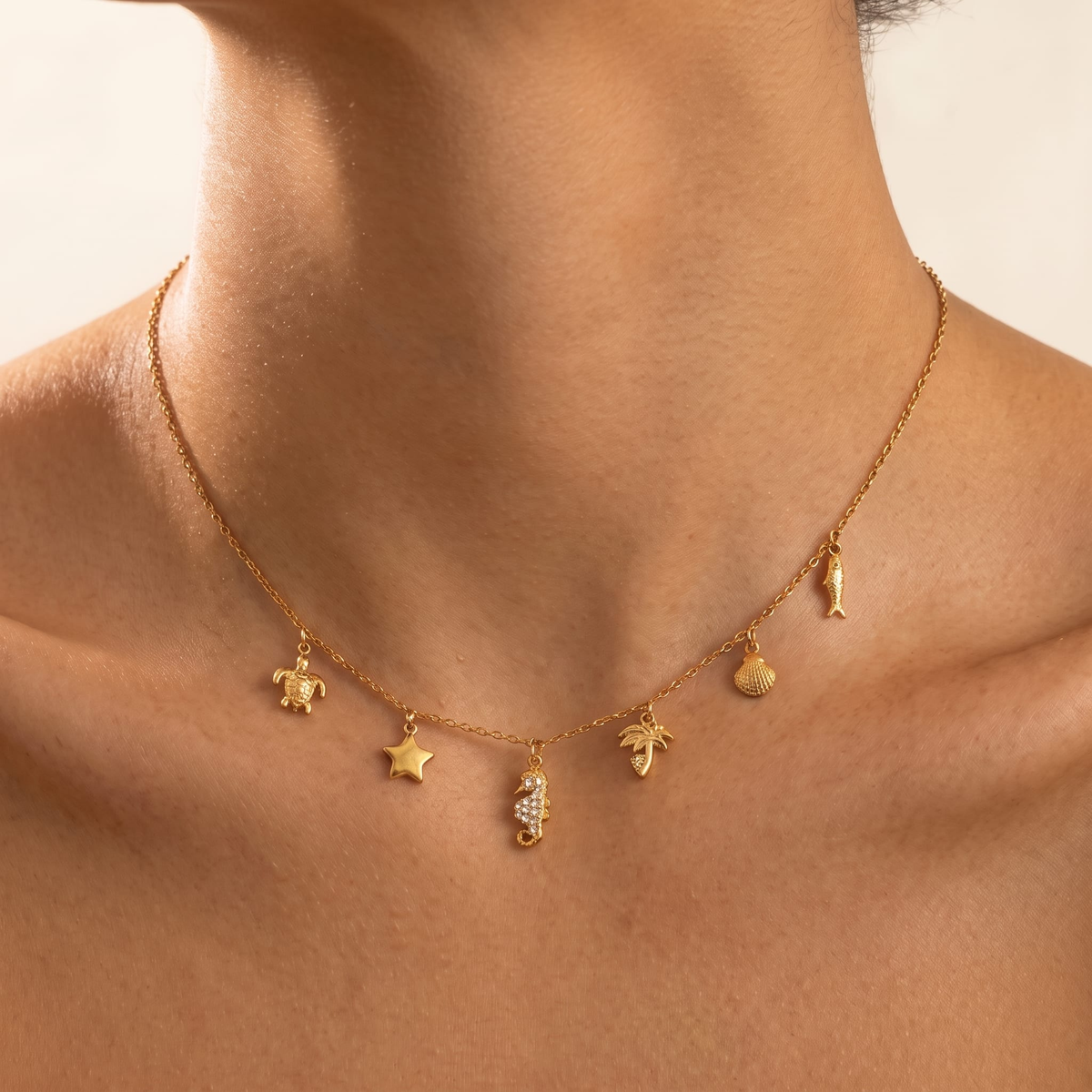 Woman wearing the Ramona sea charms gold necklace at the collarbone, featuring ocean charms