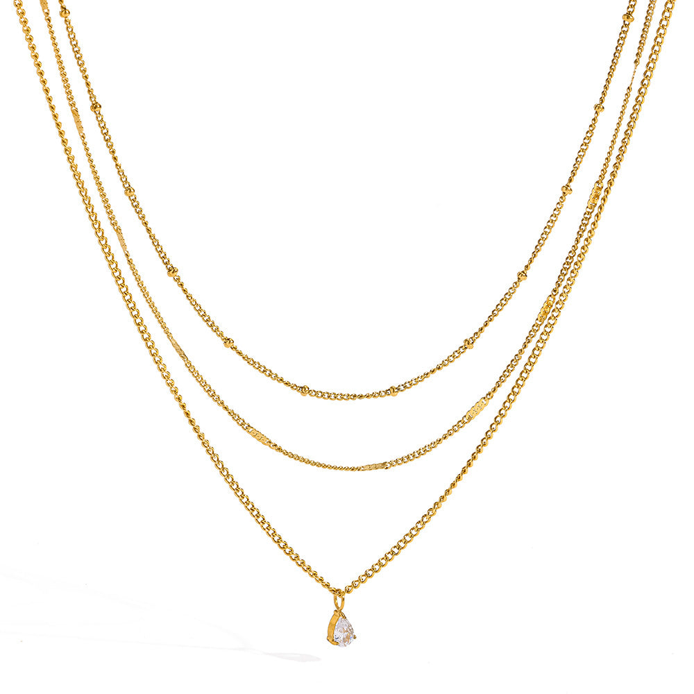Raphaëlle layered teardrop gold necklace: satellite, bar-link and teardrop crystal chains on white