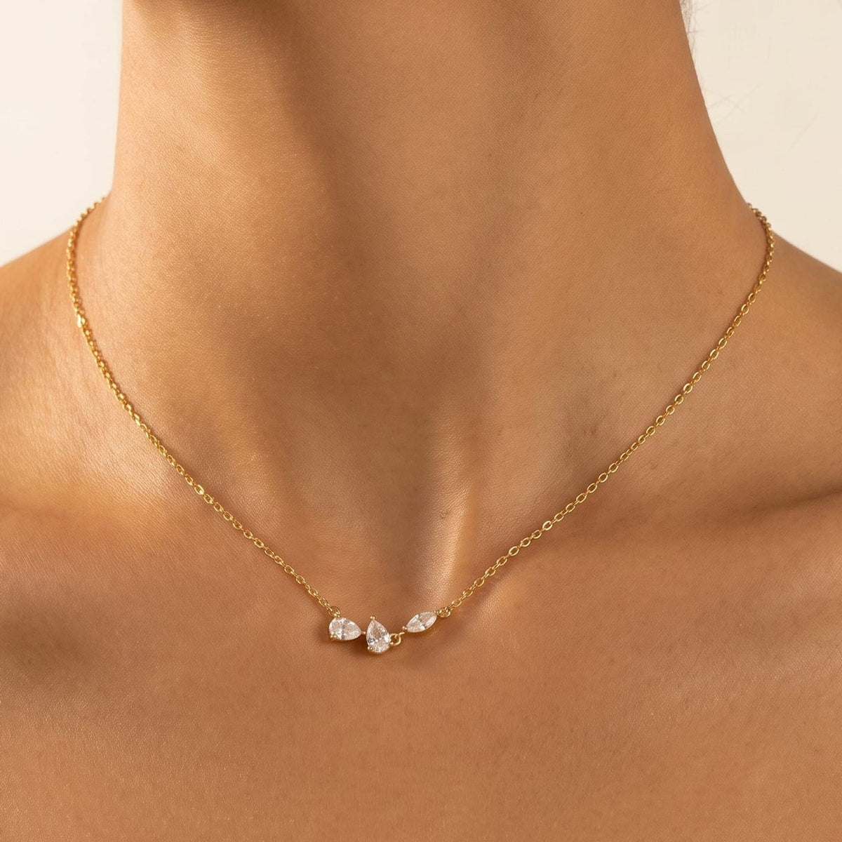 Woman wearing the Rosalie pear cluster gold necklace at the collarbone