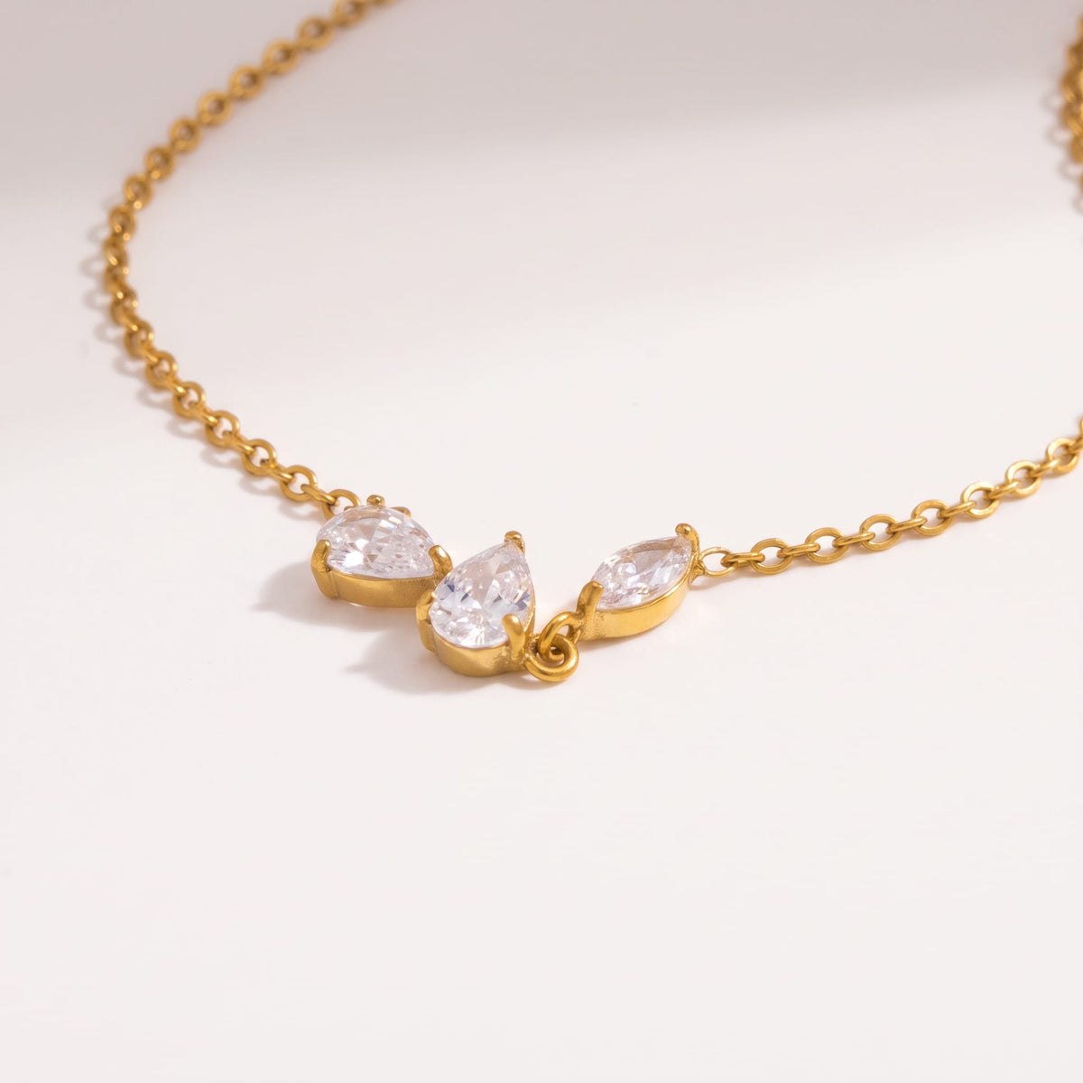 Rosalie pear cluster gold necklace on a smooth white background with soft shadows