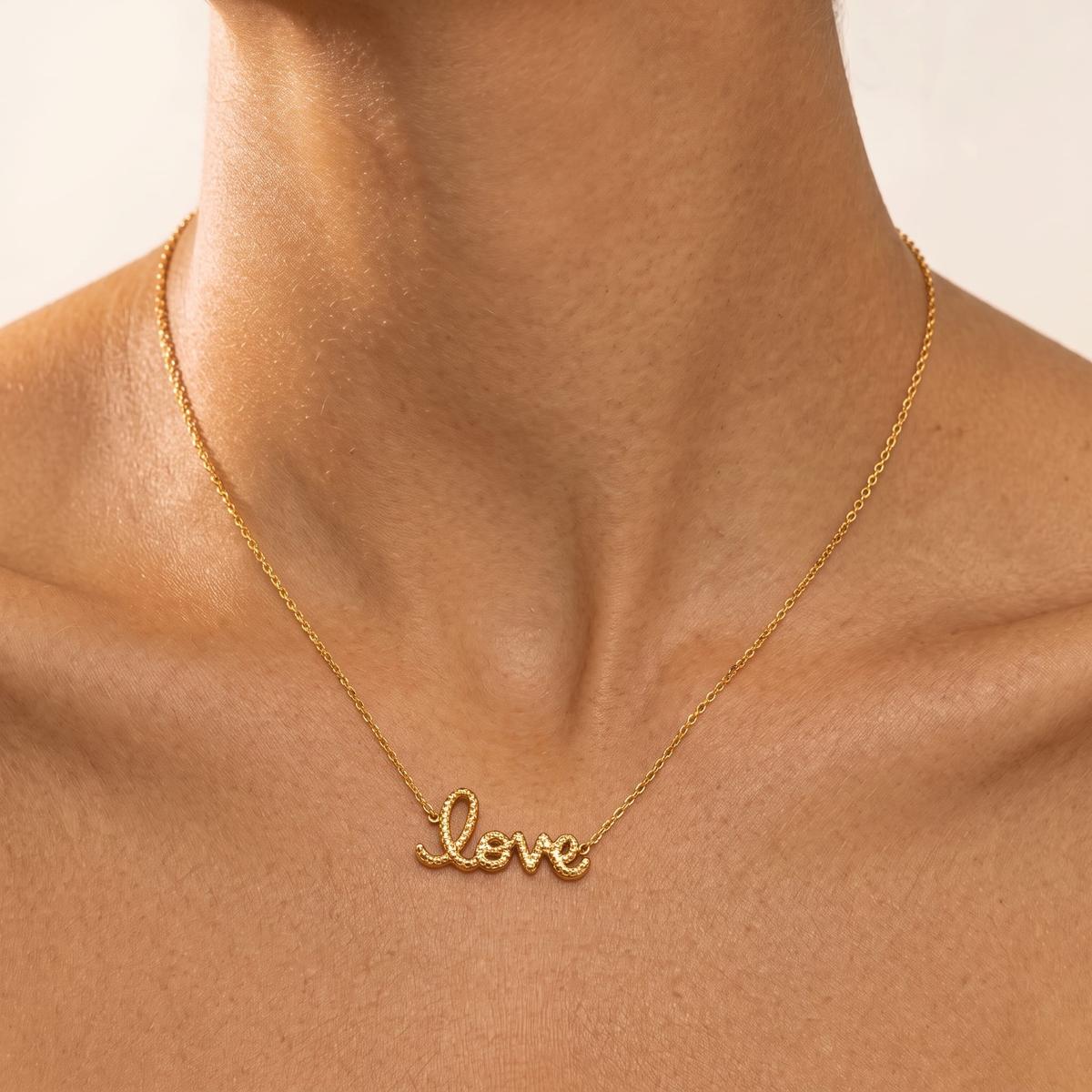 Woman wearing the Rosalie rope love script gold necklace at the collarbone