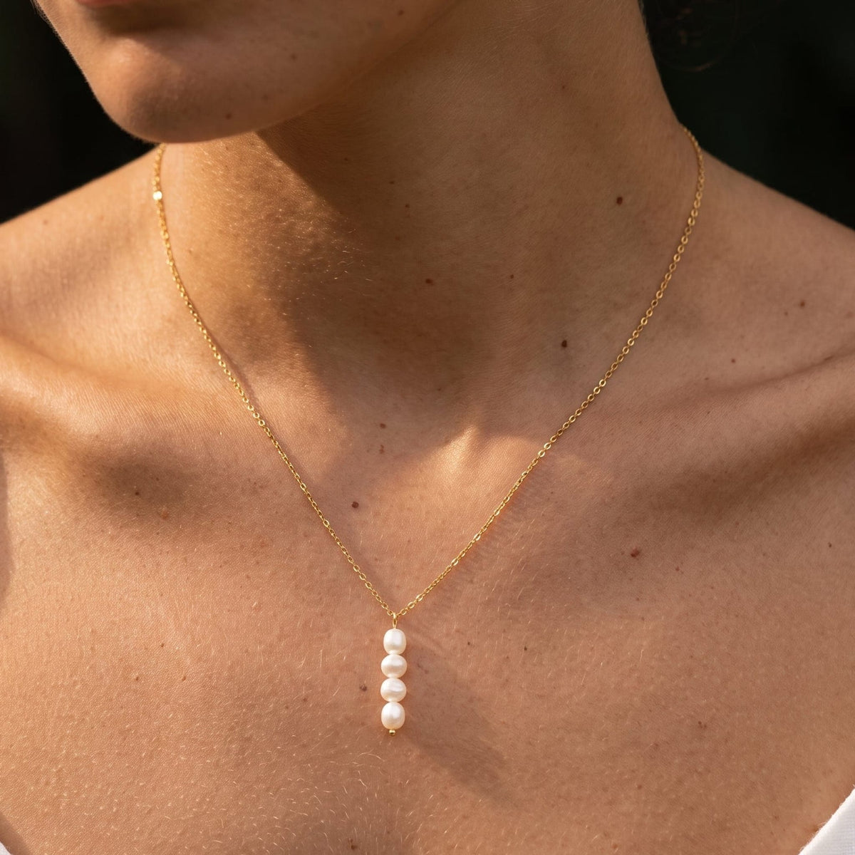 Woman wearing the Simone stacked pearl gold necklace at the collarbone
