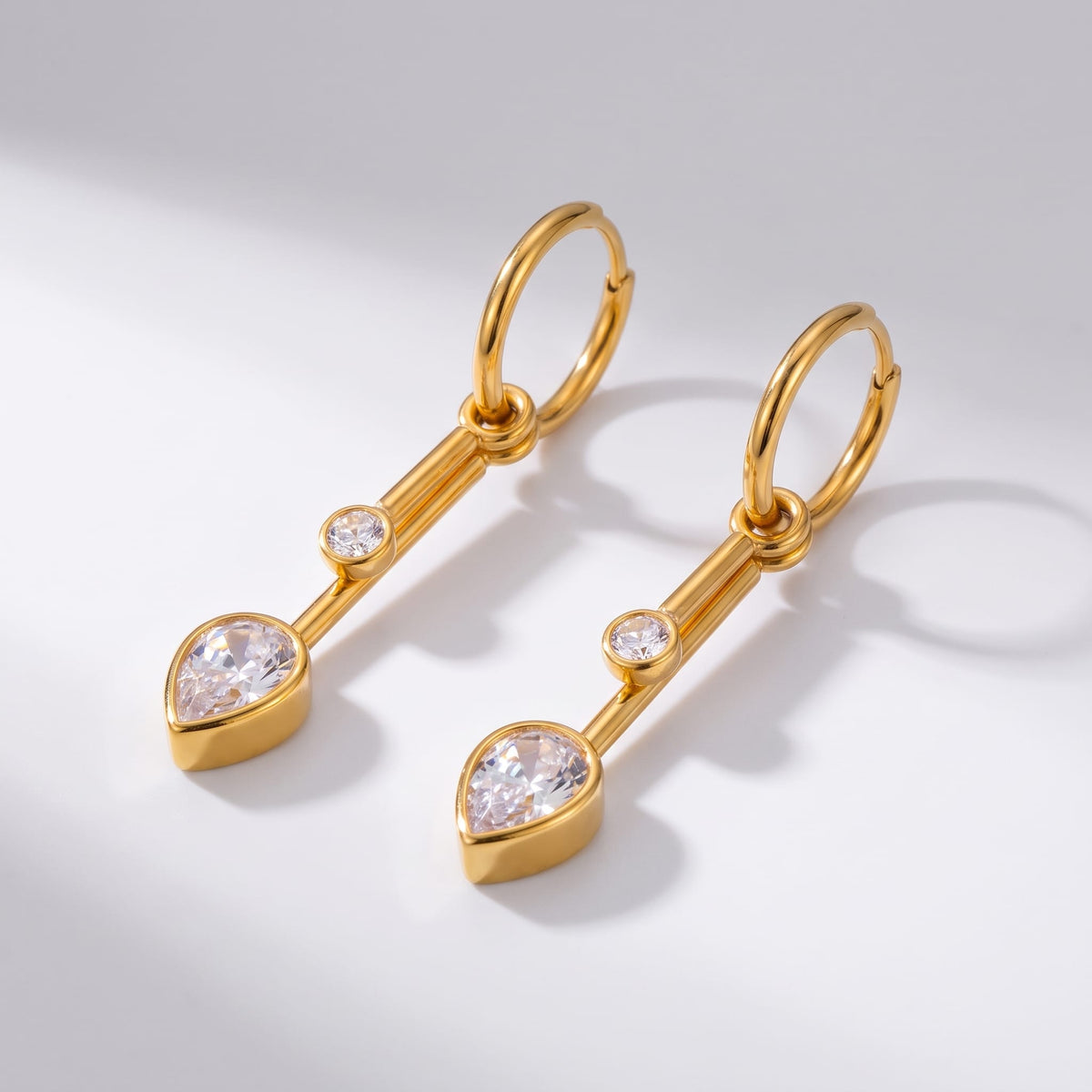 Sixtine crystal bar gold earrings on a light grey background with soft shadows