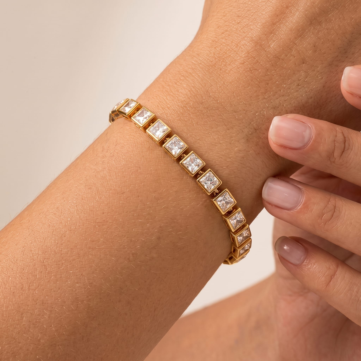 Woman wearing the Valentina princess tennis gold bracelet on the wrist, featuring square crystals
