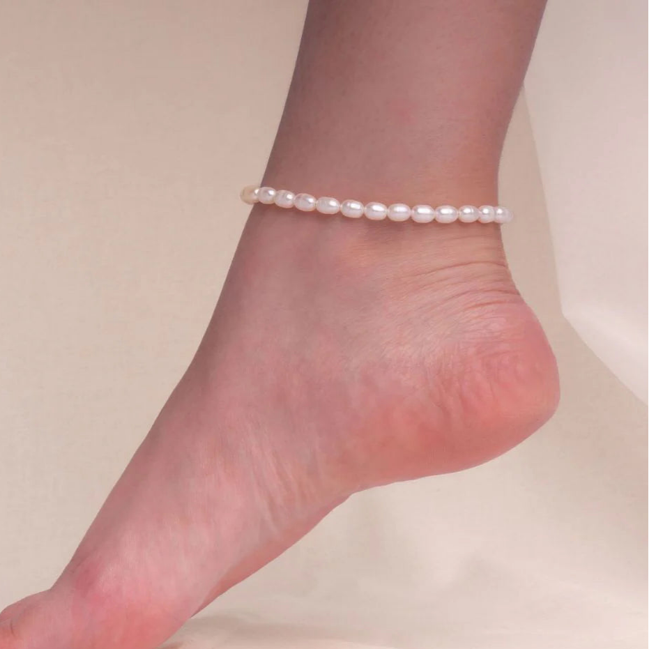 Olivia freshwater pearl anklet on a raised bare foot, a row of small oval pearls at the ankle