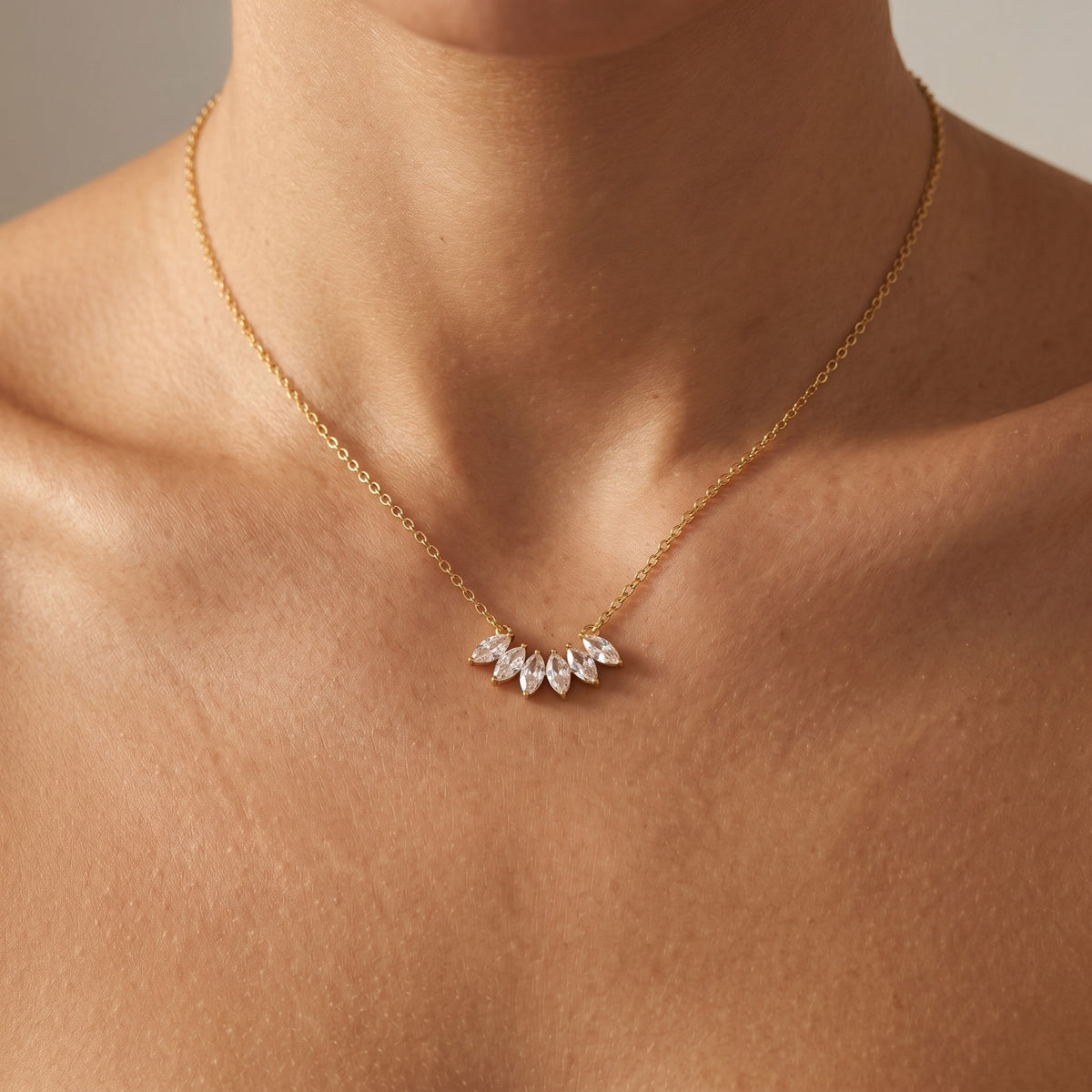 Woman wearing the Élodie gold necklace, a fan of marquise crystals resting just below the collarbone