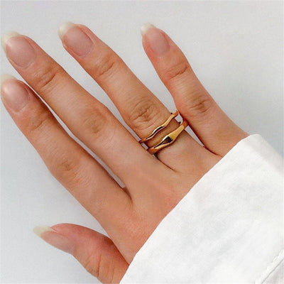 Hand wearing the Dianne stacker ring set in gold, two slim wavy bands stacked on one finger