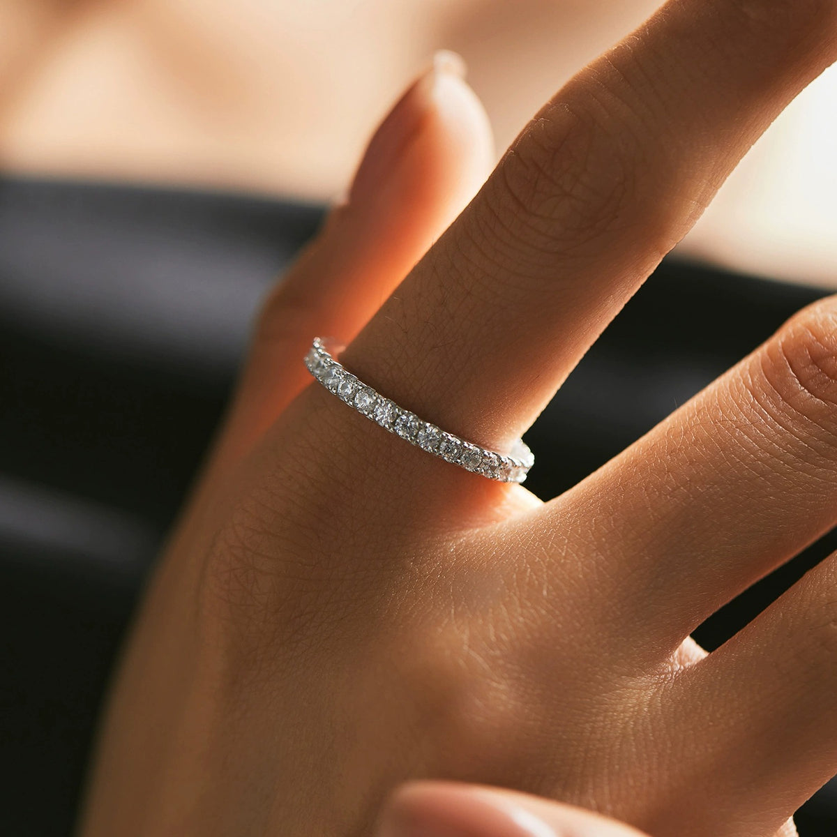 Woman wearing the Lydia eternity silver band, a thin row of round crystals, against a dark top
