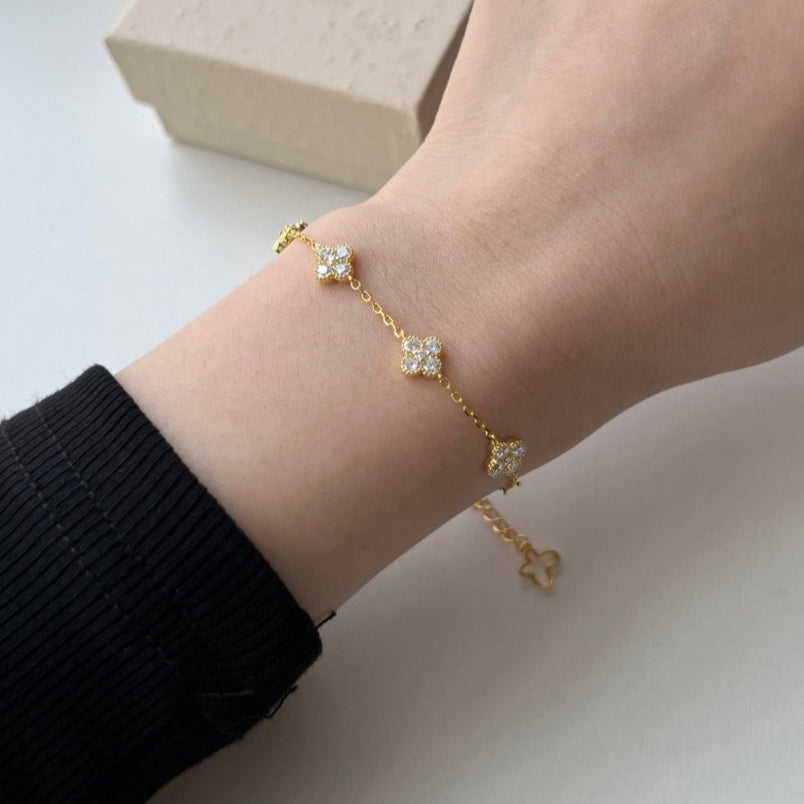 Woman wearing the Aurélie Clover Crystal bracelet in gold, clear crystal clovers spaced along the chain