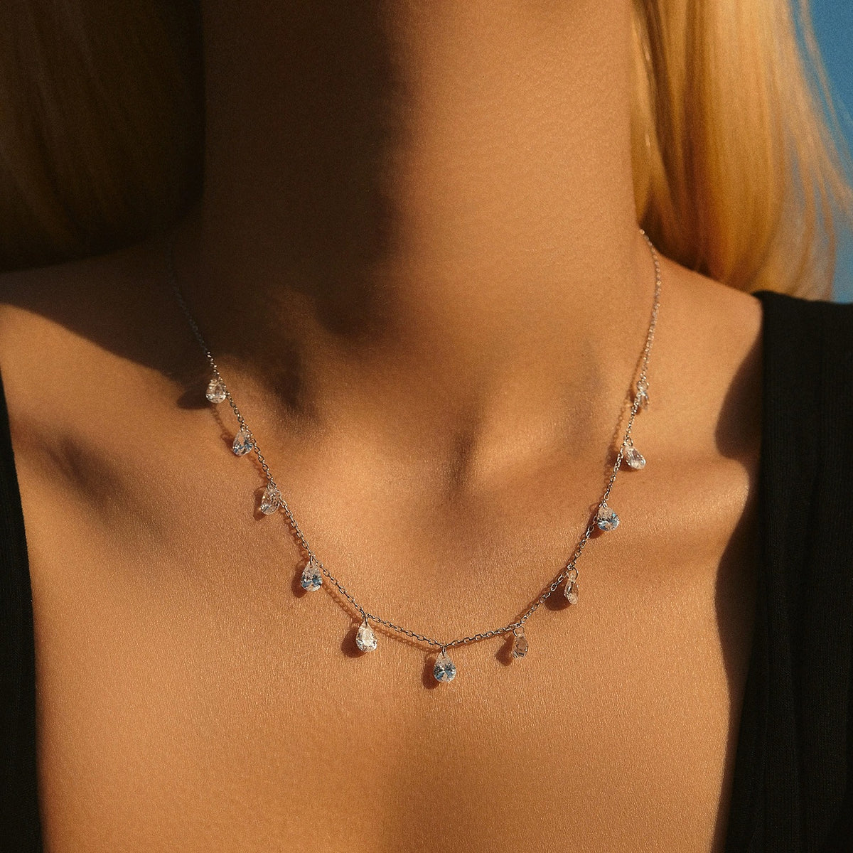 Woman wearing the Elise silver necklace with teardrop crystals hanging along the chain